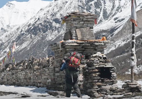 A trekker with a backpack in Manaslu circuit trek and old chorten in background